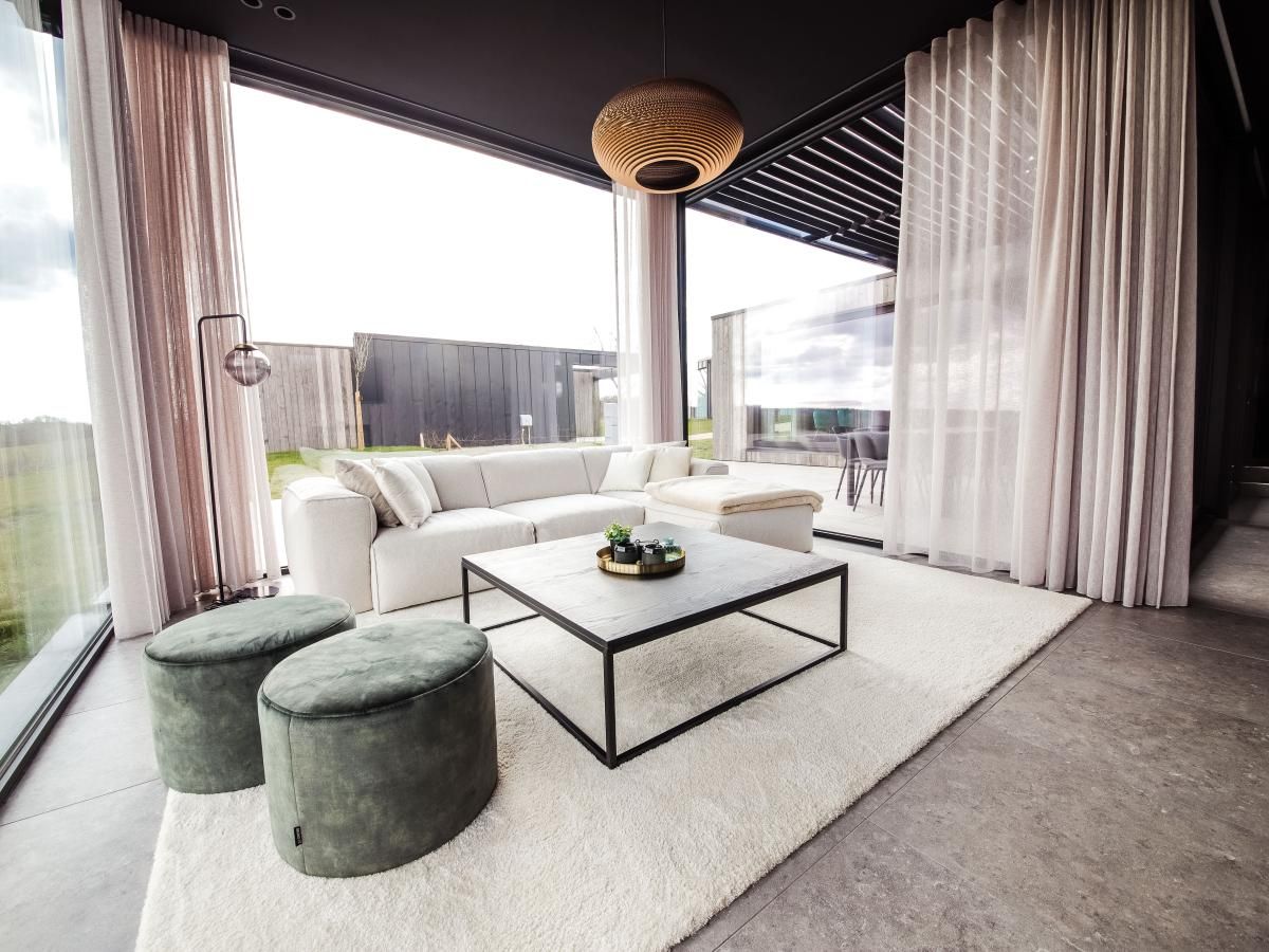 Modernes Wohnzimmer im Ferienhaus La Ruree, Heure, Ardennen, Belgien, mit stilvoller Einrichtung und grossen Fenstern fuer natuerliches Licht.