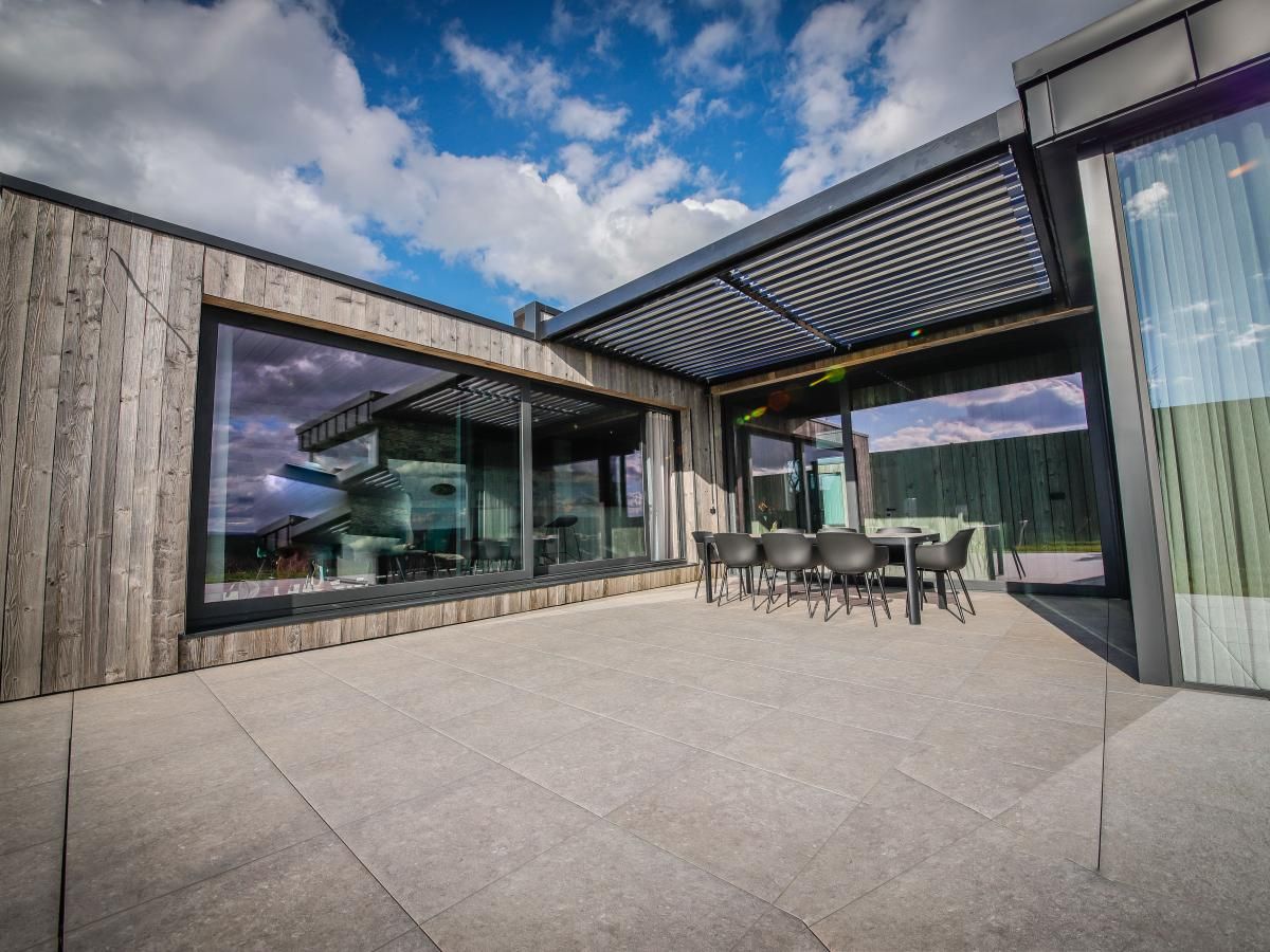 Geniessen Sie die geraeumige Terrasse des Ferienhauses La Ruree in Heure, Ardennen, Belgien, mit herrlichem Blick auf die natuerliche Umgebung.