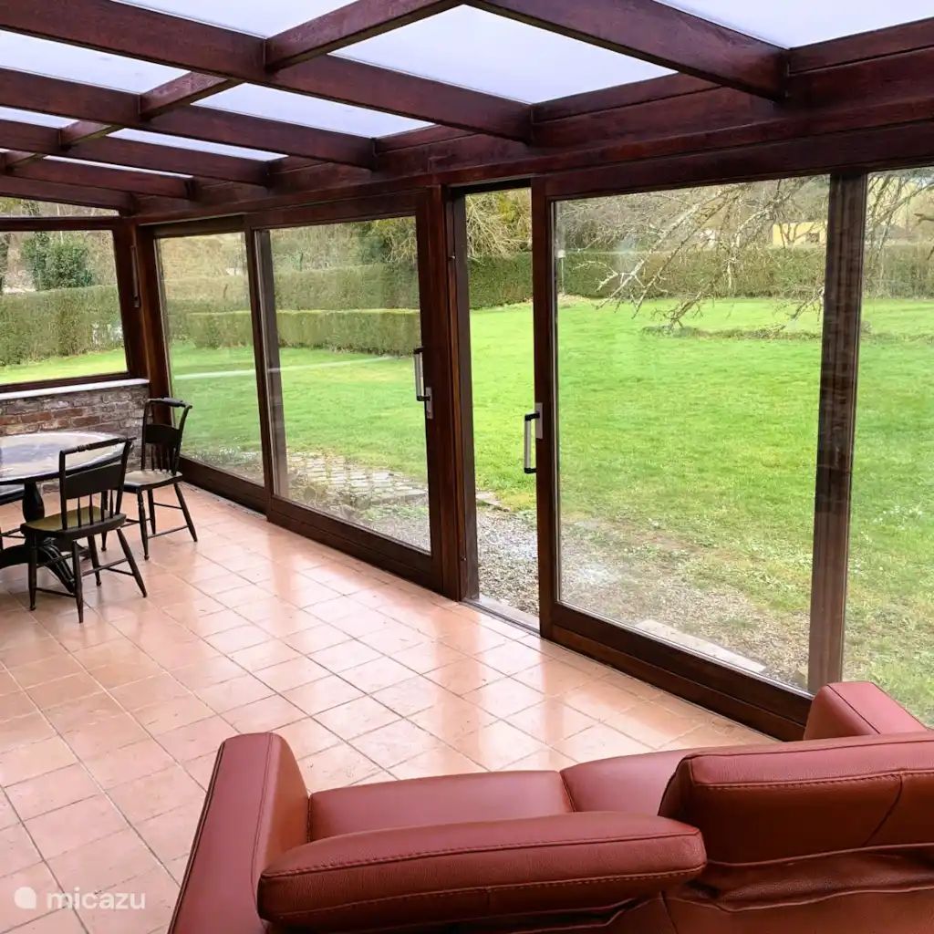 Veranda der Villa La Meuse - De Maas in Dinant, Ardennen, Belgien, mit Blick auf den gruenen Garten vom Ferienhaus aus.