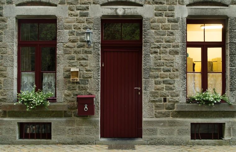 Charmantes Ferienhaus in Purnode, in den Ardennen, Belgien, mit rustikaler Steinfassade und einladender roter Tuer.