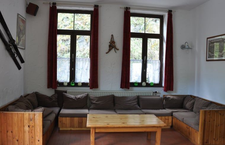 Gemuetliches Wohnzimmer von Cottage in Purnode, Ferienhaus in den Ardennen, Belgien, mit bequemer Sitzecke und Blick auf die Natur.