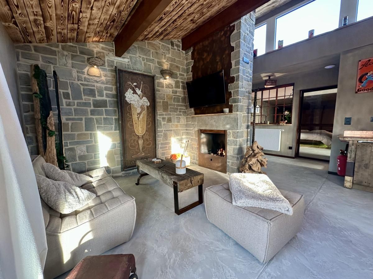 Cozy living room of Chez Brigitte, a vacation home in Durbuy, Ardennes, with stone walls and stylish decor.
