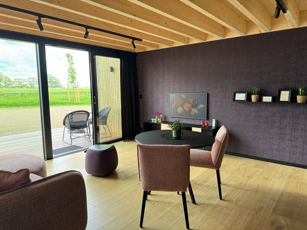 Gezellige woonkamer van Escapade Naturelle in de Ardennen, met uitzicht op terras en natuur.