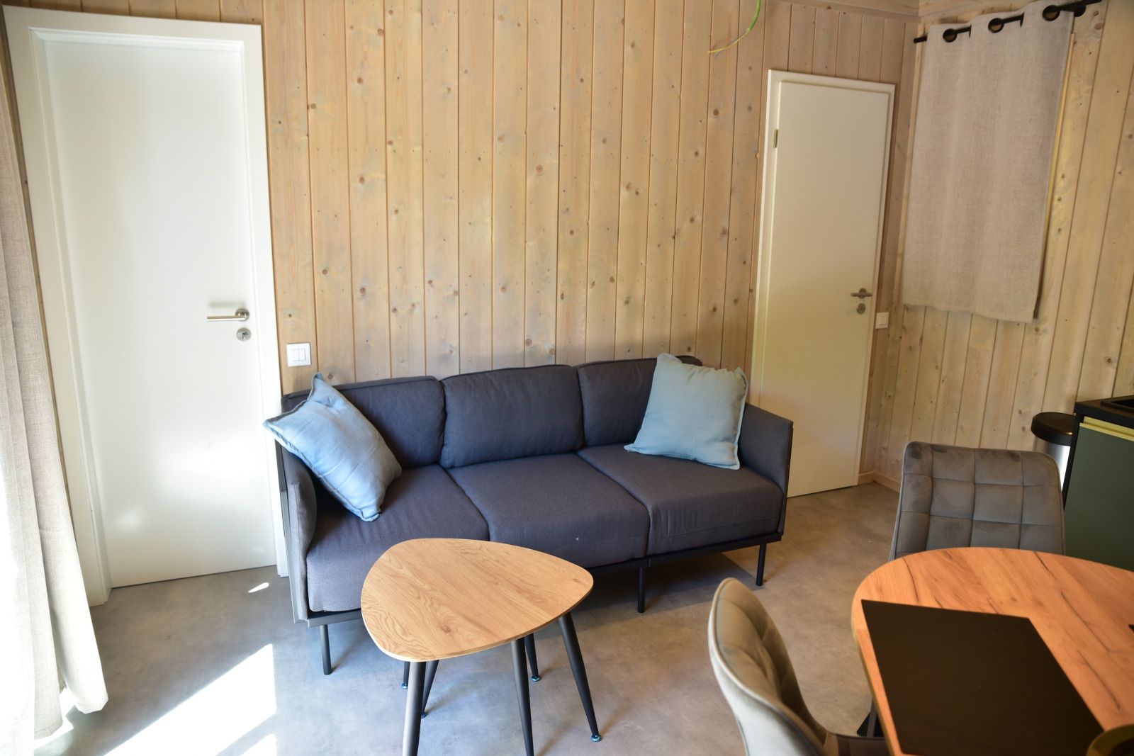 Cozy living room of Ecolodge vacation home in Houffalize, Ardennes, Belgium, with comfortable sofa and wooden interior.