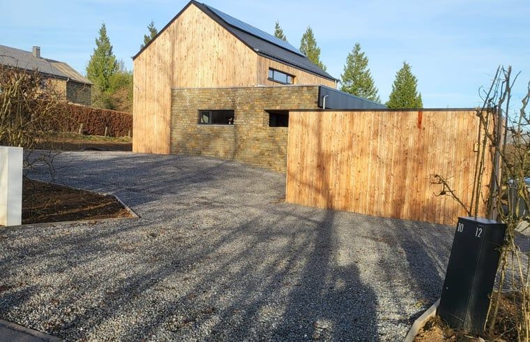 Cottage in Grandmenil, cottage in the Ardennes, Belgium with modern wooden facade and spacious driveway surrounded by nature.