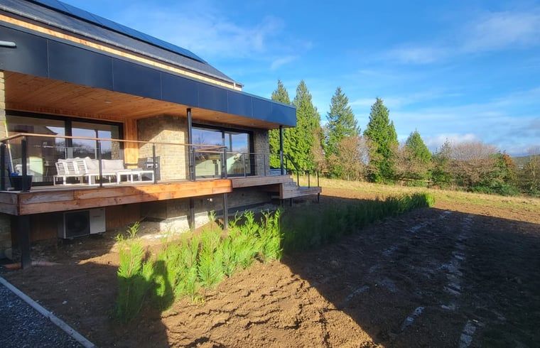 Veranda of Cottage in Grandmenil, located in Ardennes, Belgium, overlooking green nature and sunny garden.