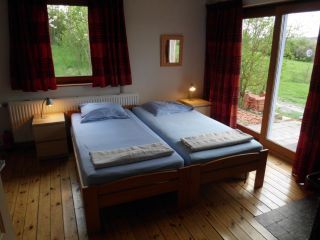 Slaapkamer in La Terra vakantiehuis, Durbuy, met twee eenpersoonsbedden en terras.