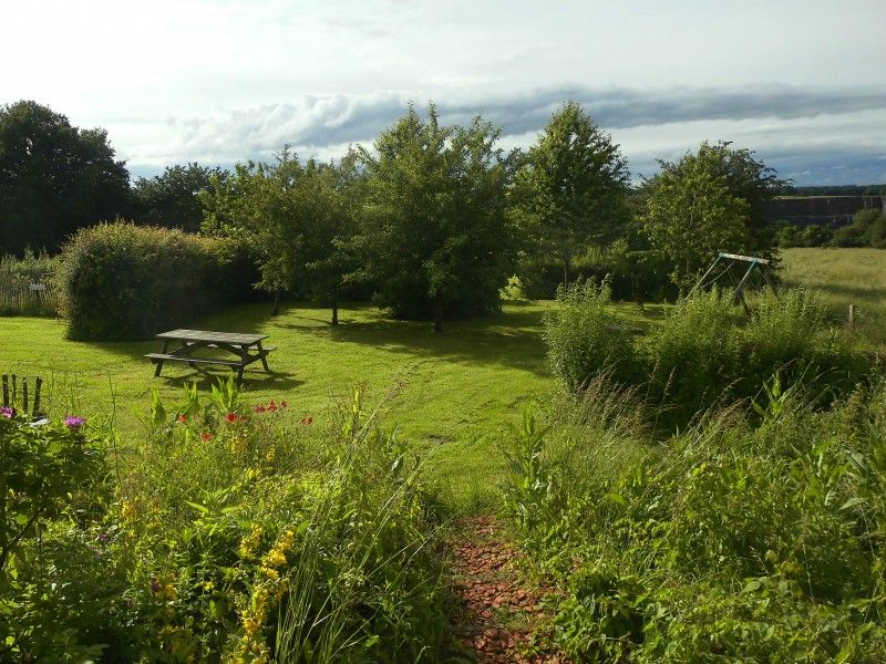 Picknickplek in de tuin van La Terra vakantiehuis, Durbuy, omringd door bomen.