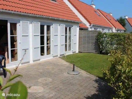 Geniet van de zonnige tuin en het terras bij Seaside Village, huisje 77, een charmant vakantiehuis in Vosseslag, De Haan, Belgische kust.