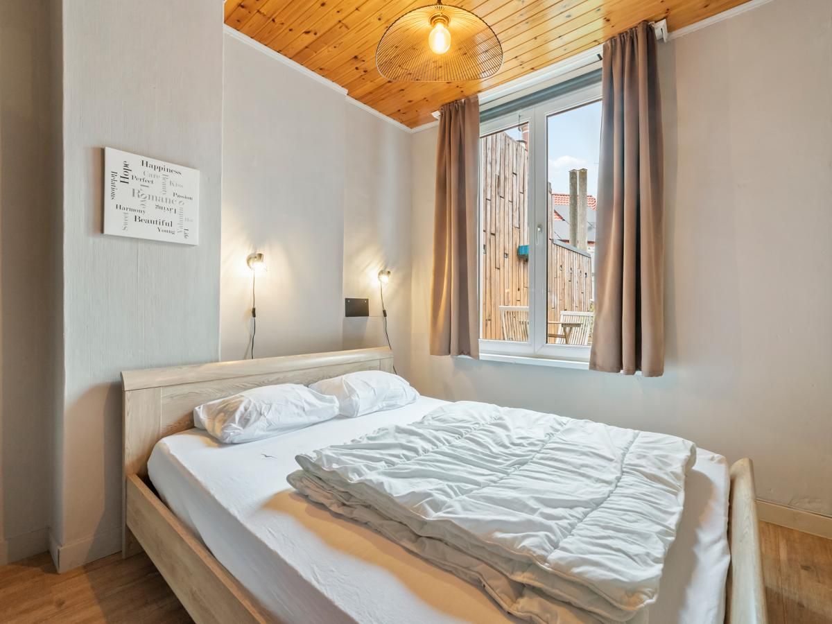 Gezellige slaapkamer in vakantiehuis Ijzerstraat - 52, Blankenberge, Belgische kust, met houten plafond en uitzicht op de omgeving.