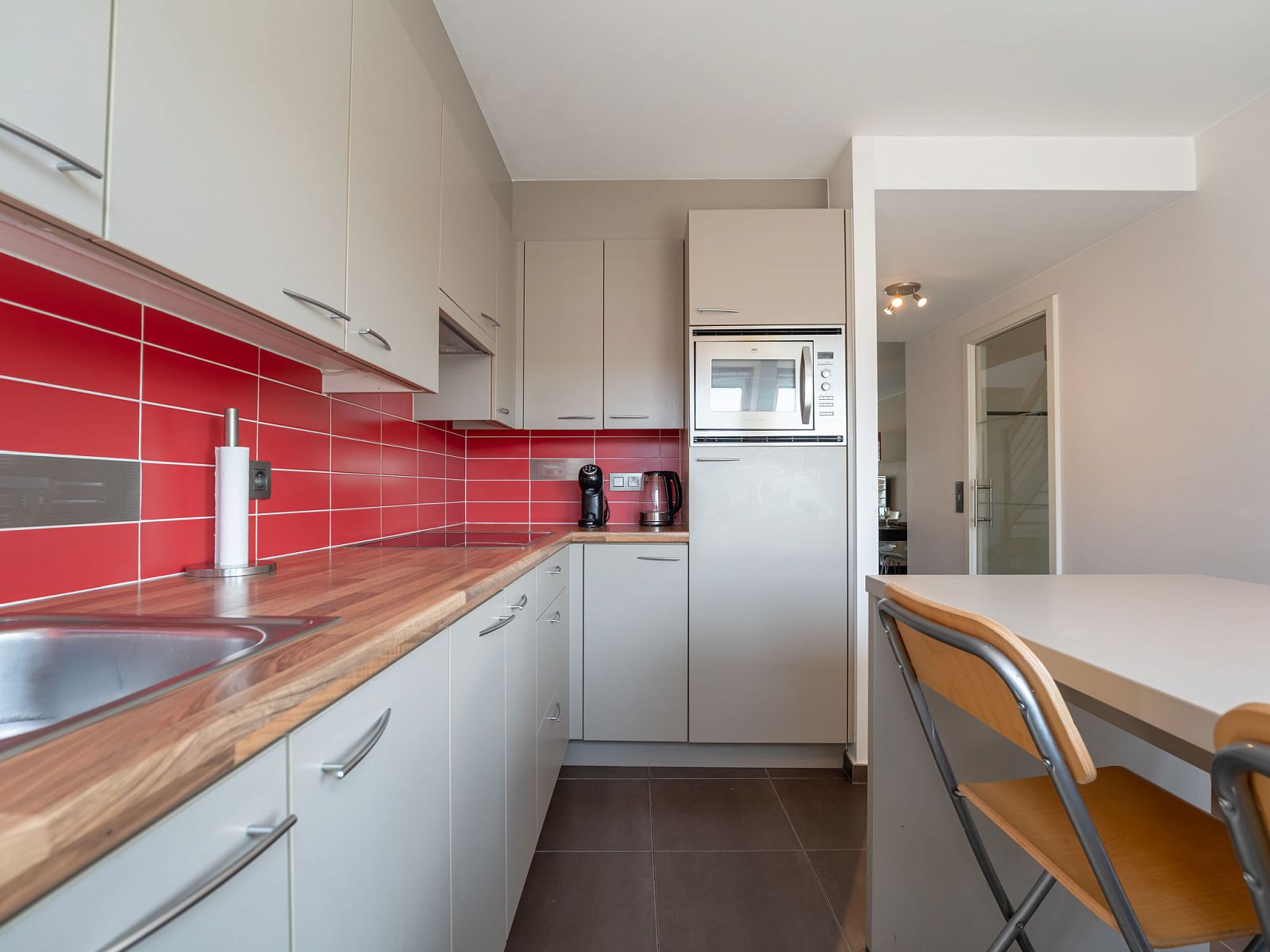 Modern kitchen in Apartment Ter Duyne, Bredene on the Belgian coast, with red tiles and sleek decor for a comfortable stay.