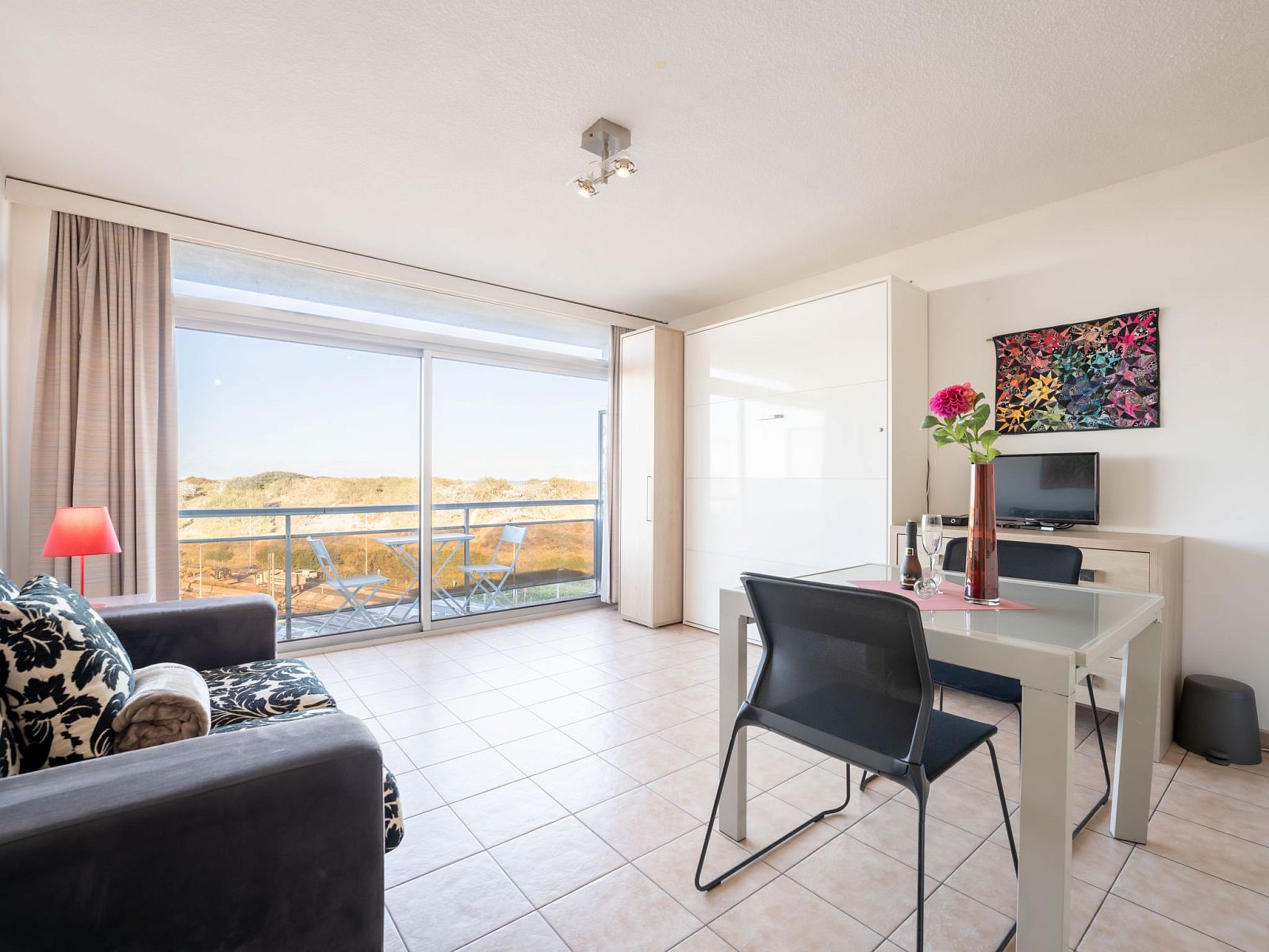 Bright living room of Apartment Studio 62-705 in Bredene, Belgian coast, overlooking dunes and modern furnishings.