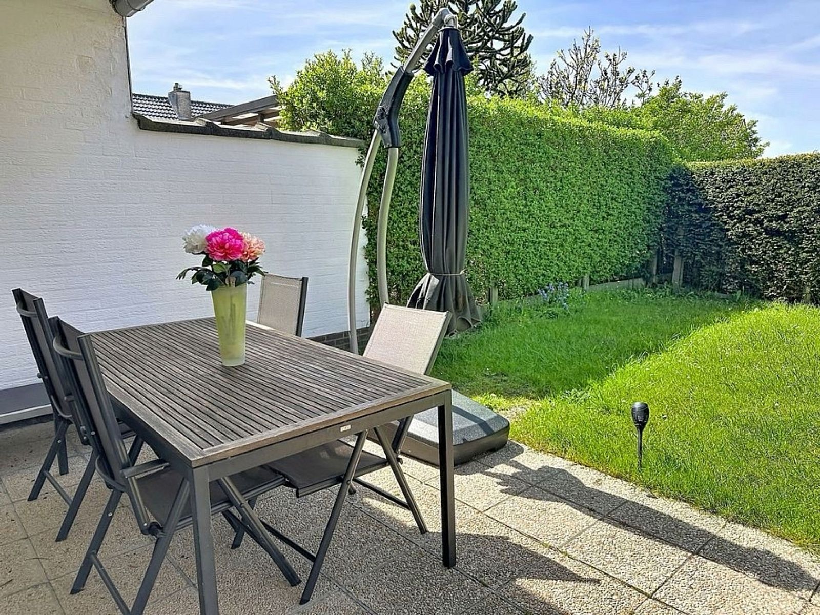 Gezellige eetkamer in Vakantiehuis Ruiterlaan, Bredene, Belgische kust, met houten meubels en uitzicht op de tuin.