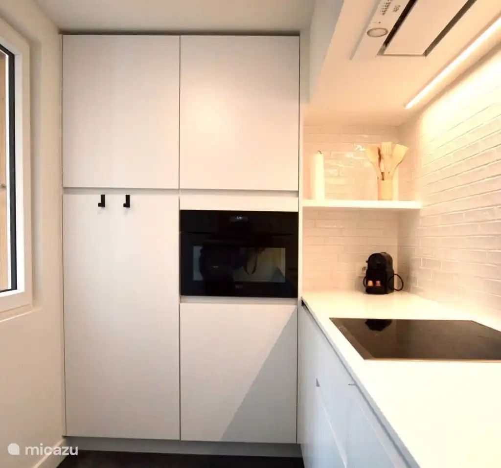 't Silte Apartment with a terrace in Middelkerke features a modern kitchen with sleek white cabinets and a stylish countertop on the Belgian coast.