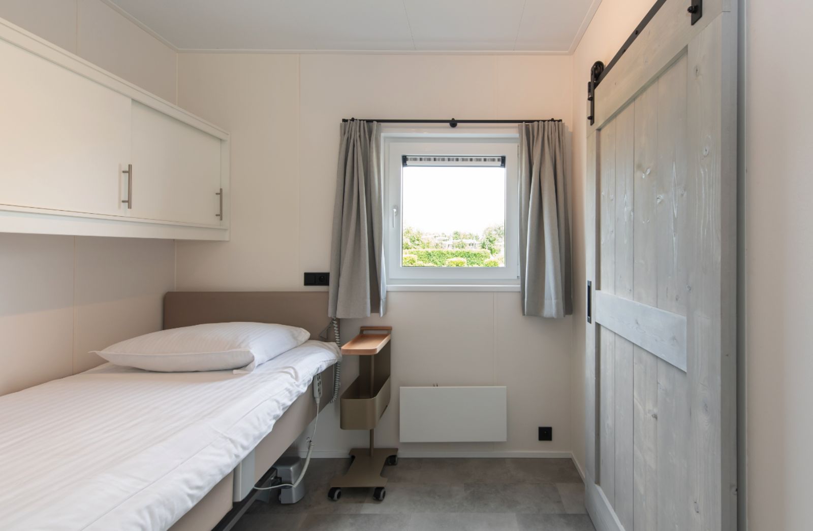 Knusse slaapkamer in Access Lodge, een vakantiehuis in Nieuwpoort aan de Belgische kust, met een comfortabel eenpersoonsbed en rustgevend uitzicht.