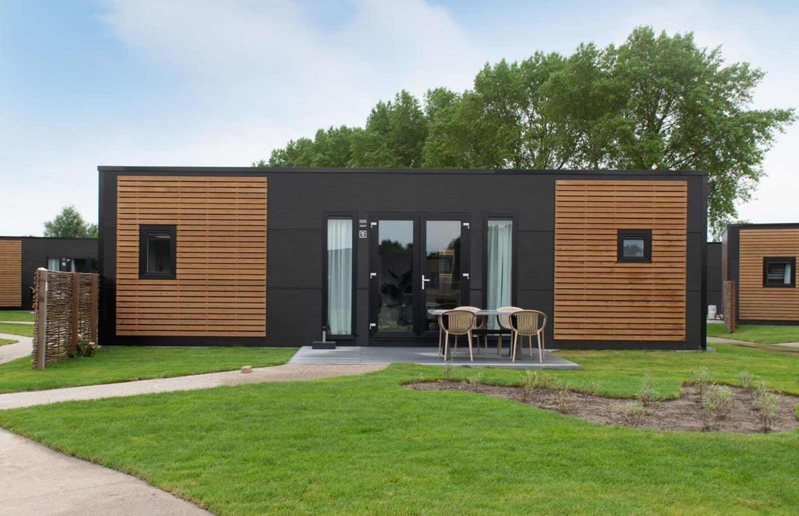 Wood Lodge in Nieuwpoort, Belgische kust, een moderne vakantieaccommodatie met veranda en groene omgeving, ideaal voor hondenliefhebbers.