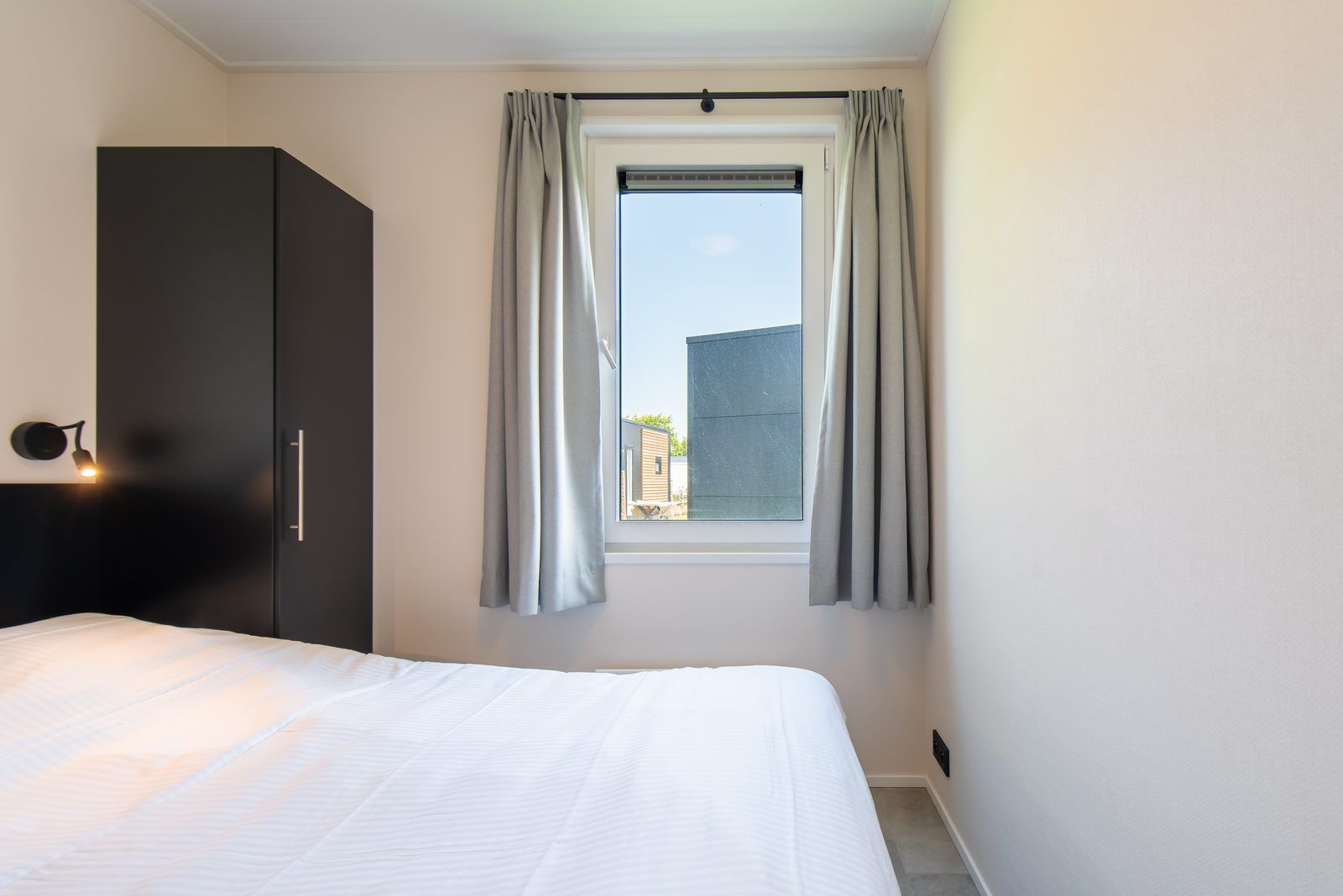 Slaapkamer in Wood Lodge, een vakantiehuis in Nieuwpoort aan de Belgische kust, met comfortabel bed en uitzicht op de omgeving.