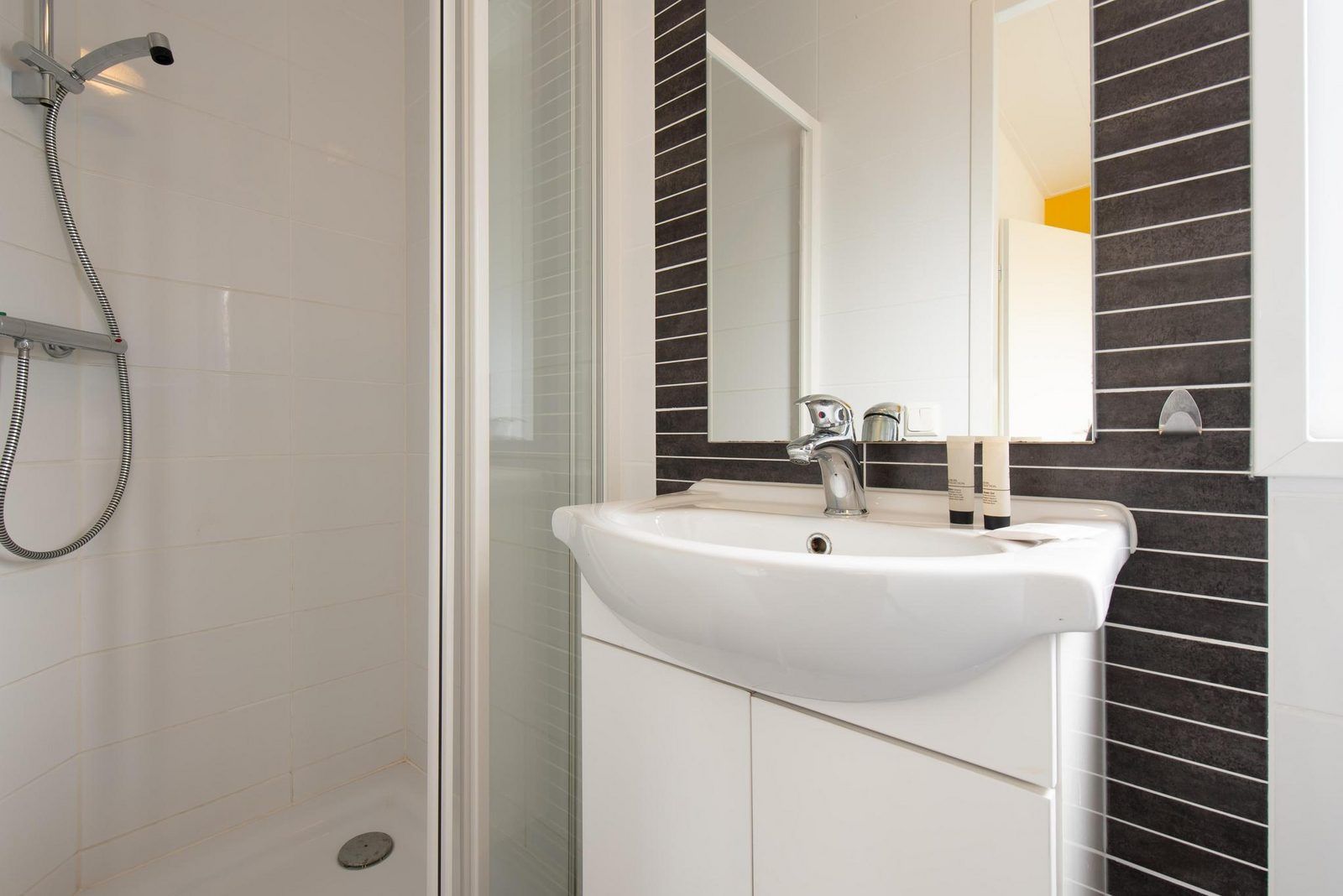 Moderne badkamer in Comfort Lodge, een vakantiehuis in Nieuwpoort aan de Belgische kust, met stijlvolle wastafel en douche.