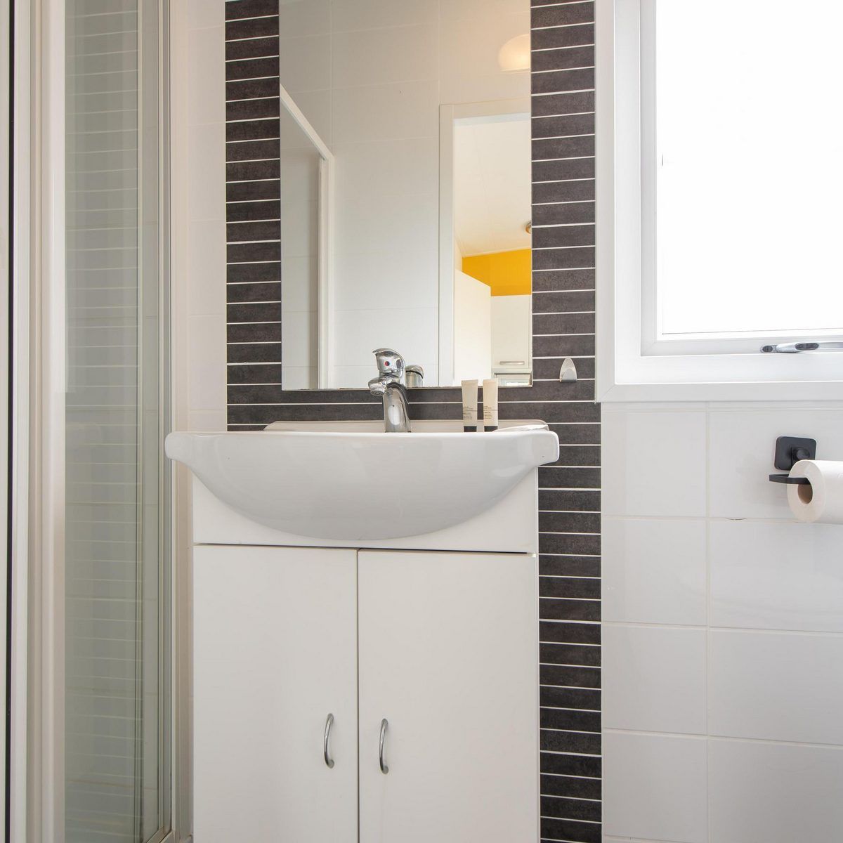 Moderne badkamer in Comfort Lodge, vakantiehuis in Nieuwpoort aan de Belgische kust, met stijlvolle wastafel en natuurlijk daglicht.