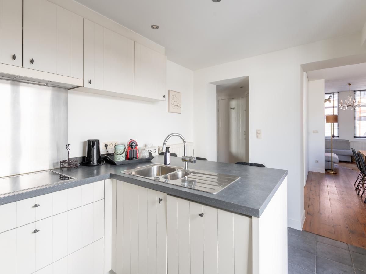 Moderne keuken in vakantiehuis Notre Dame, Nieuwpoort aan de Belgische kust, met elegante inrichting en toegang tot lichte woonkamer.