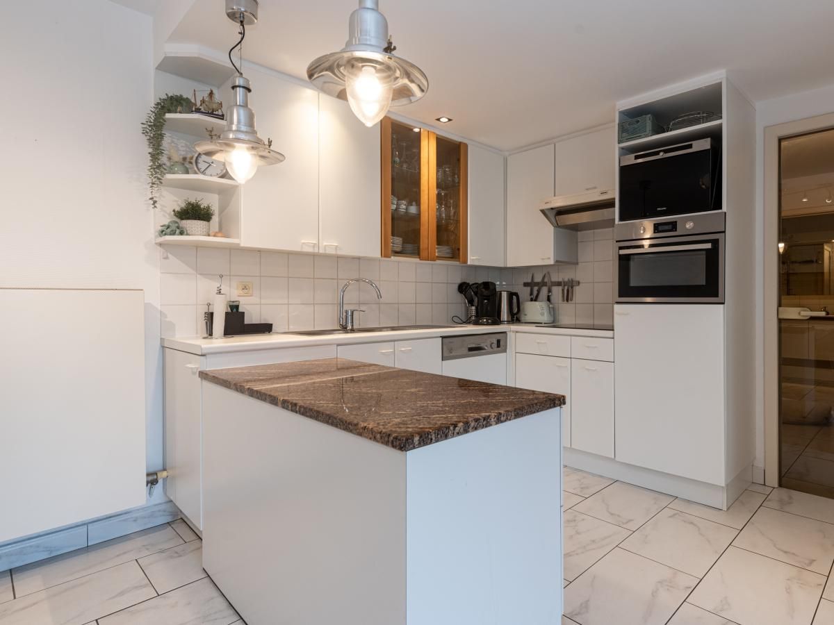 Moderne keuken in vakantiehuis Reigersnest in Nieuwpoort aan de Belgische kust, compleet met stijlvolle apparatuur en gezellige eetruimte.