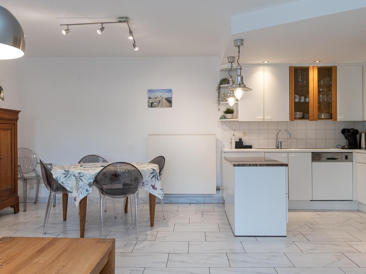 Gezellige woonkamer van vakantiehuis Reigersnest in Nieuwpoort, Belgische kust, met comfortabele bank en uitzicht op groene omgeving.