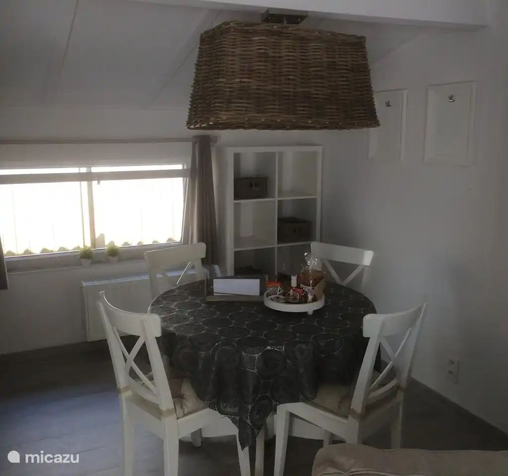 Gemuetliche Essecke in "Het Toeval", einem Ferienhaus in Oostduinkerke an der belgischen Kueste, mit einer rustikalen Haengelampe und einfallendem Tageslicht.