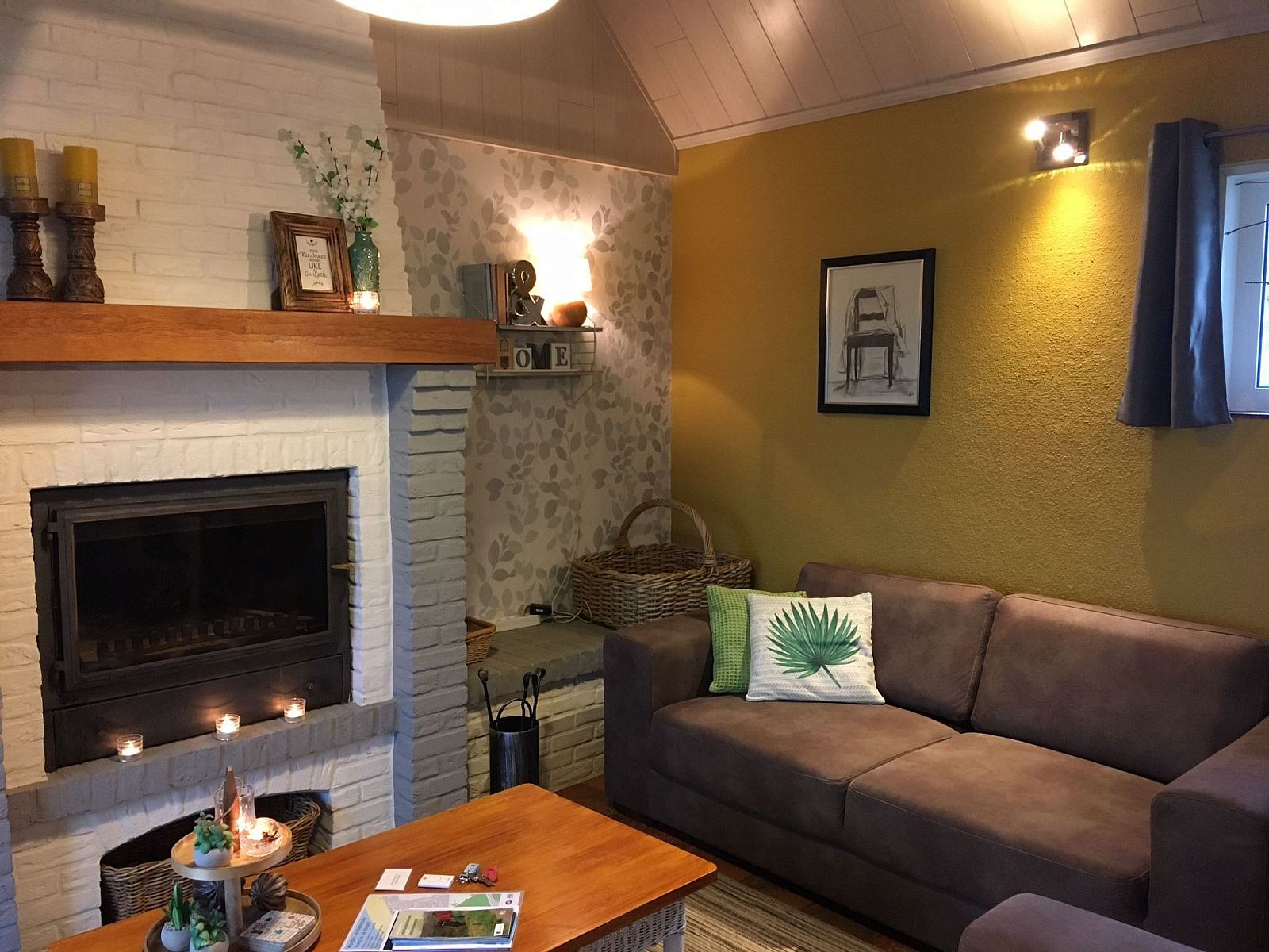 Gemuetliches Wohnzimmer des Ferienhauses Windekind mit Blick auf die Felder in De Panne, belgische Kueste, mit Kamin und gemuetlicher Sitzecke.