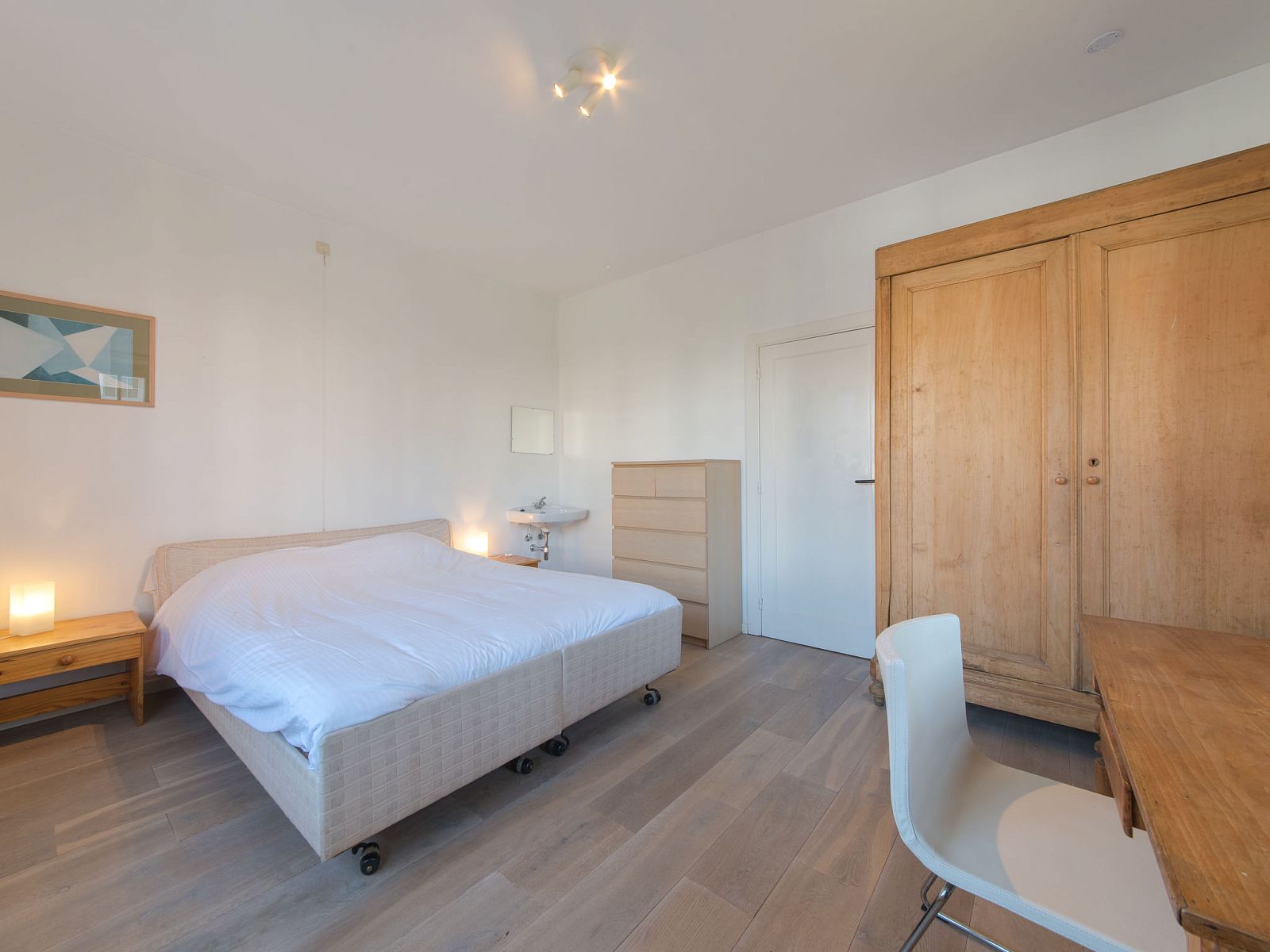 Slaapkamer in Appartement Jong & Blij 2 op de begane grond met tuin in De Haan, Belgische kust, met comfortabel bed en houten interieur.