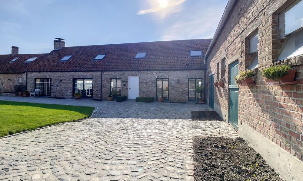 Hoeve Langhof vakantiehuis in De Haan, Belgie met een charmante binnenplaats en rustieke stenen muren.
