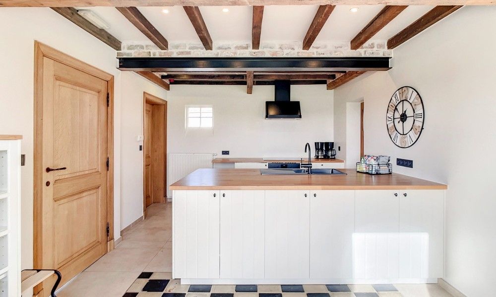 Moderne keuken in Hoeve Langhof vakantiehuis, De Haan, met houten balken en ruime werkbladen.
