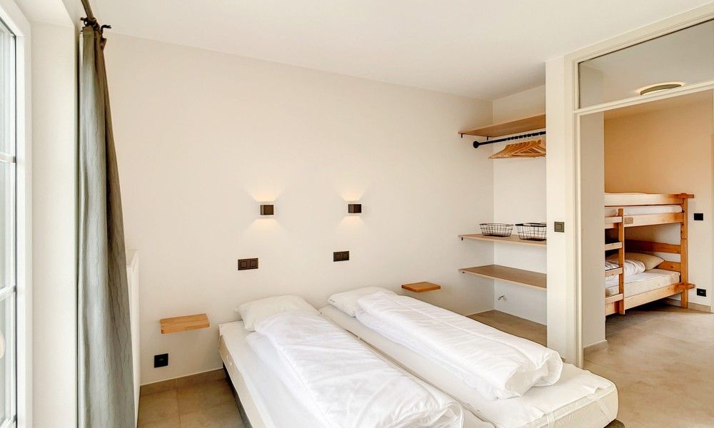 Slaapkamer met stapelbedden en eenpersoonsbedden in Hoeve Langhof vakantiehuis, De Haan.