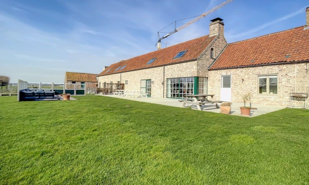 Uitgestrekt grasveld bij Hoeve Langhof vakantiehuis, De Haan, ideaal voor buitenactiviteiten.