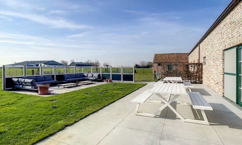 Gezellige loungehoek op het terras van Hoeve Langhof vakantiehuis, De Haan, met uitzicht op de natuur.