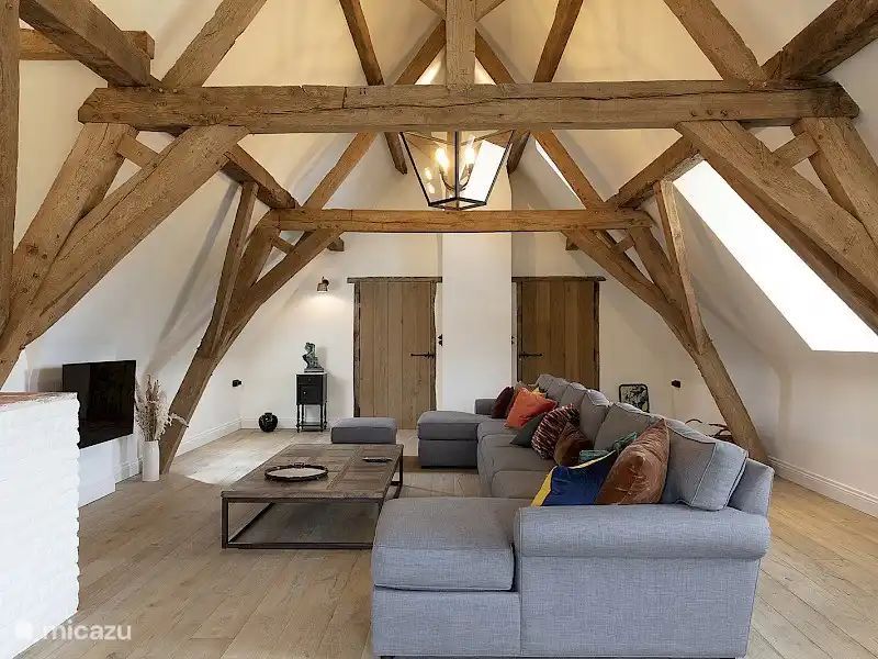 Gezellige woonkamer in Huis Potaerde, een vakantiehuis in Brussel, met houten balken en comfortabele zithoek voor een ontspannen verblijf.