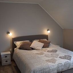 Gezellige woonkamer in Reutelhoeve vakantiehuis in Zonnebeke, West-Vlaanderen met open haard en comfortabele stoelen.