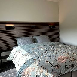 Luxurioeses Schlafzimmer im Ferienhaus in PROVEN, Proven, Westflandern, Belgien, mit eleganter Bettwaesche und moderner Wandbeleuchtung.