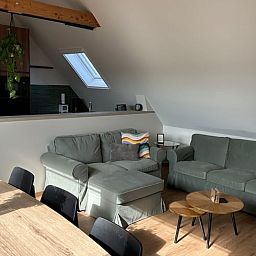 Gemuetliches Wohnzimmer im Ferienhaus in PROVEN, Westflandern, mit komfortabler Sitzecke und moderner Kueche in heimeliger Atmosphaere.