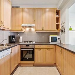 Moderne keuken in vakantiehuis Azcona Twee, Koksijde, West-Vlaanderen, Belgie met houten kasten en moderne apparatuur.