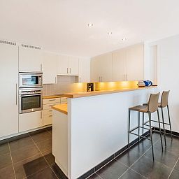 Modern kitchen in vacation home Brit Eerste, Koksijde, West Flanders. Stylish interior with bar and sleek finish.