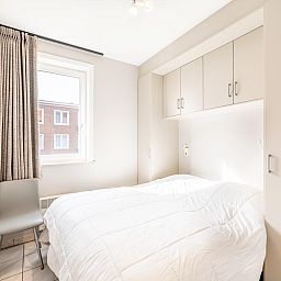 Sfeervolle slaapkamer in Delfien Eerste vakantiehuis, Koksijde, met licht interieur en uitzicht op de omgeving van West-Vlaanderen, Belgie.