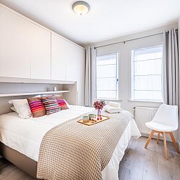 Sfeervolle slaapkamer van Gaston Lejeune tweede vakantiehuis in Koksijde, West-Vlaanderen met comfortabel bed en licht interieur.