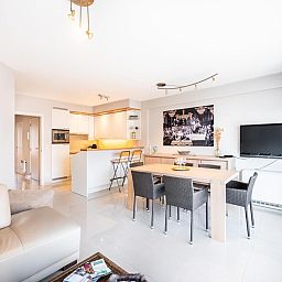 Modernes Wohnzimmer des Ferienhauses Guernsey second in Koksijde, Westflandern, Belgien mit offener Kueche und grosszuegigem Essbereich.