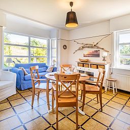 Gezellige eetkamer in Juvamy gelijkvloers, vakantiehuis in Koksijde, West-Vlaanderen, met veel licht en comfortabele zithoek.