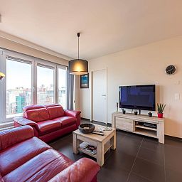 Gezellige woonkamer in vakantiehuis De Dijk zesde, Koksijde, met moderne inrichting en uitzicht op de stad West-Vlaanderen, Belgie.
