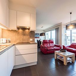 Moderne keuken en gezellige woonkamer in vakantiehuis De Dijk zesde, Koksijde, West-Vlaanderen, ideaal voor een ontspannen verblijf.