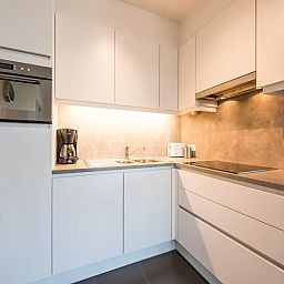Moderne keuken in vakantiehuis De Dijk zesde, Koksijde, Belgie, met strakke witte kasten en ingebouwde apparatuur.