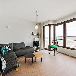 Lichte woonkamer in De Meeuwen derde vakantiehuis met zeezicht in Koksijde, West-Vlaanderen, Belgie.