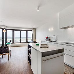 Stijlvolle keuken en woonkamer met zeezicht in De Meeuwen derde vakantiehuis, Koksijde, West-Vlaanderen, Belgie.