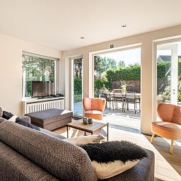 Lichte woonkamer van vakantiehuis Tranquil in Koksijde, West-Vlaanderen met uitzicht op zonnig terras en tuin.
